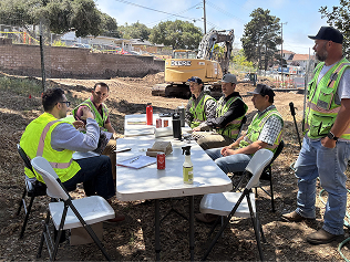 A photo of the Constructable team wearing safety gear at a job site meeting with a customer to discuss ideas for new software features